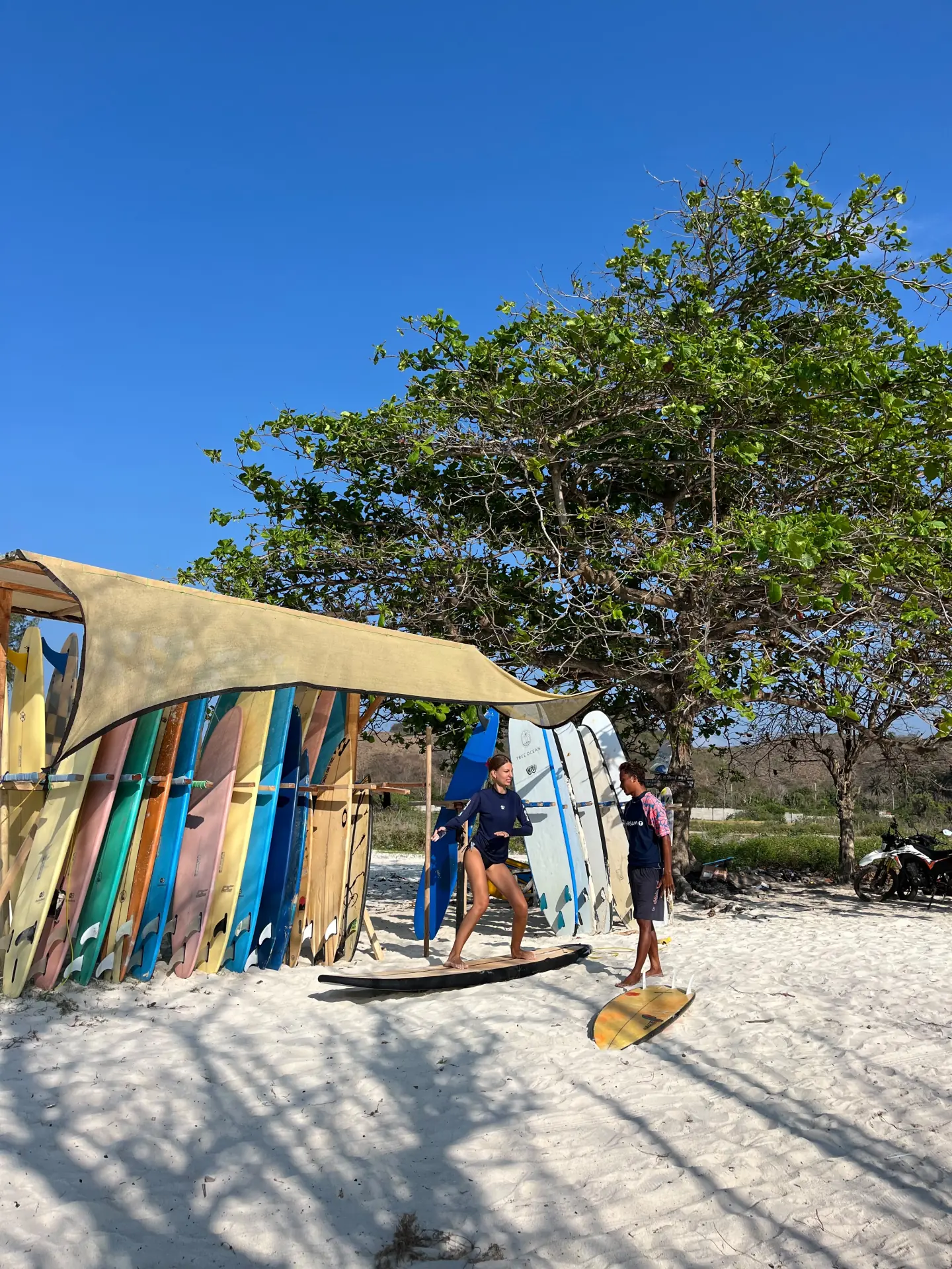 A local surf coach helping a student beside a colourful board rack
