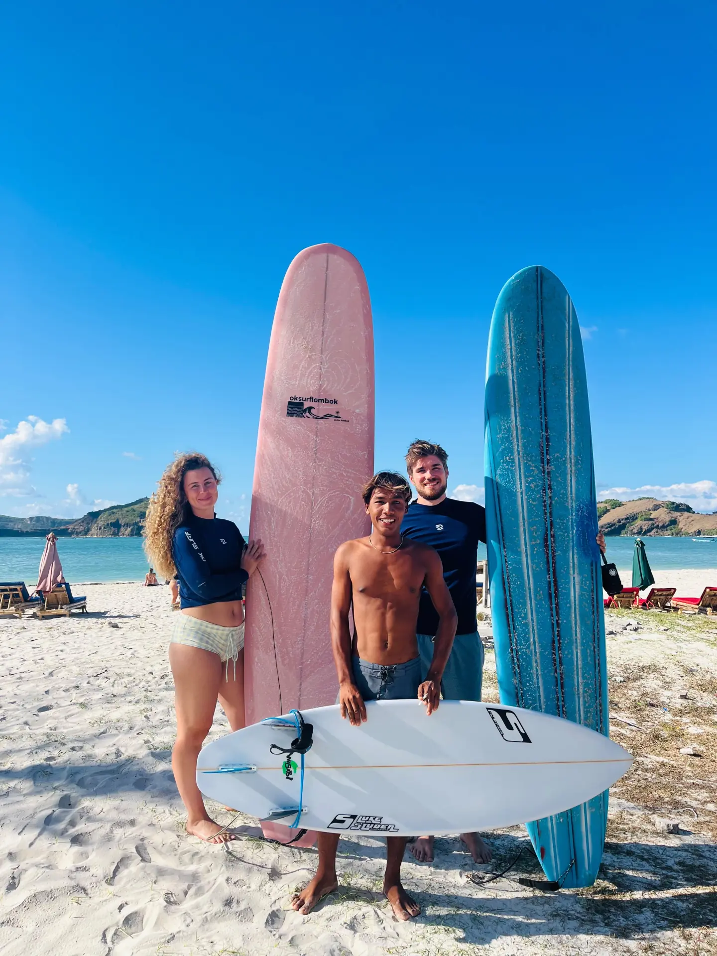 Two guests with their local surf coach and boards